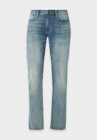 Сини избелели дънки с прав крачол с предни джобове, халки за колан и копче на обикновен фон.
