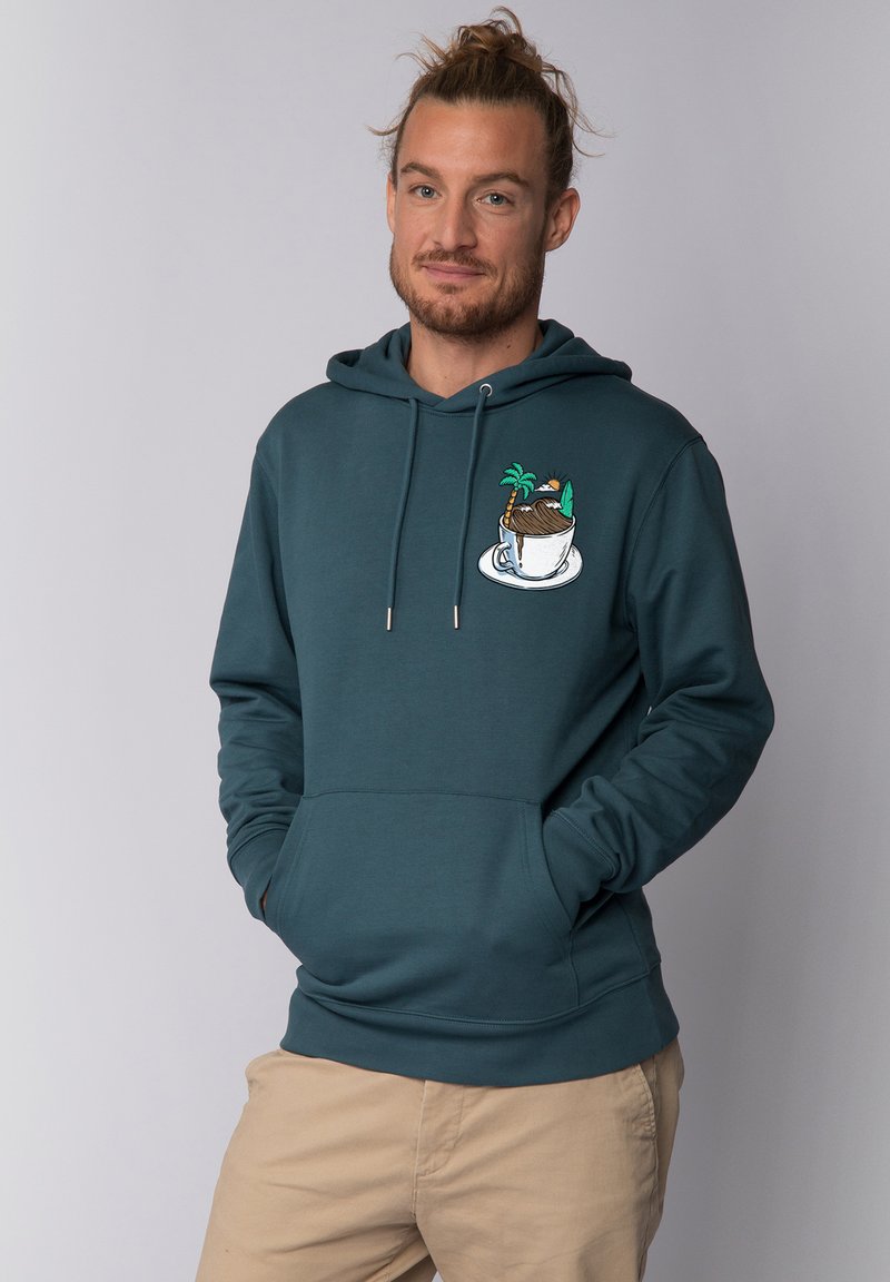 Sweat à capuche teal foncé avec une poche frontale et des cordons, décoré d'un design de tasse colorée avec un palmier et un accent de désert.
