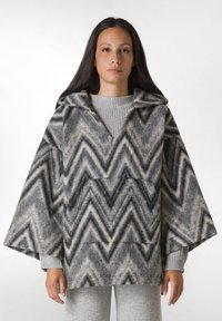 Fleece poncho i grå med et chevronmønster. Har en bred pasform, stort hætte og lomme foran. Struktureret stof med blød overflade.