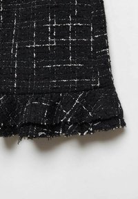 Zwarte tweedstof met witte stiksels, voorzien van een gerimpelde zoom en een getextureerd oppervlak. De textiel heeft een ruitpatroon over de gehele lengte.