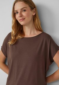 Bruine, kortemouwen top met een wijde halslijn. Gemaakt van zacht materiaal, met een relaxte pasvorm en een soepele textuur. Eenvoudig, naadloos ontwerp.
