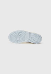 Nike-Schuhsohle aus hellblauem Gummi, mit einem strukturierten Muster aus kreisförmigen und linearen Designs für Grip und Stabilität.