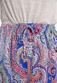 Tessuto colorato e stampato con intricati motivi paisley in rosa, blu e verde; vita elasticizzata con dettaglio di lacci regolabili.