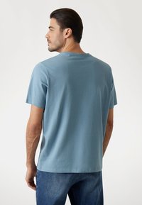 T-shirt in cotone azzurro chiaro con maniche corte, collo rotondo e vestibilità rilassata. Tessuto liscio e orlo dritto in vita.