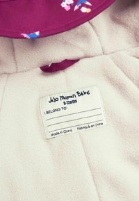 Lichtroze fleece stof met een paarse kraag met bloemenpatroon. Witte waslabel met de tekst "JoJo Maman Bébé" en maat "9-12 maanden."