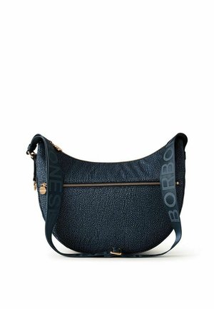 Sac bandoulière texturé bleu foncé en forme de croissant avec poche zippée et bandoulière réglable avec texte en gras.