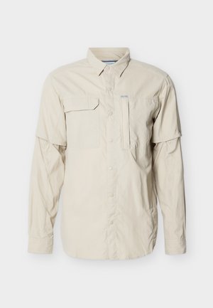 Beżowa koszula outdoorowa z długim rękawem, zapinana na guziki z przodu, z dwoma kieszeniami na piersi oraz wentylacją na zamek pod rękawami.