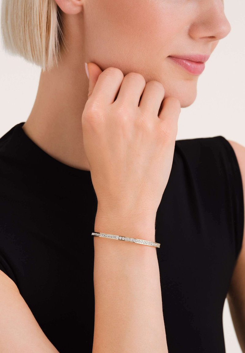 Bracciale in argento con accenti di cristallo trasparente, caratterizzato da un design elegante e minimalista. La superficie ha una texture lucida e liscia.