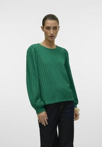 Grøn tekstureret langærmet top med rund hals og puffede ærmer, der har et ribbet mønster og en afslappet pasform. Båret sammen med mørke jeans.
