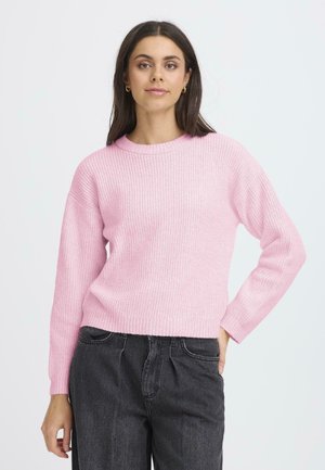 Pull en maille rose clair avec un col rond et des manches longues, doté d'une texture côtelée. Assorti à un pantalon taille haute gris foncé.