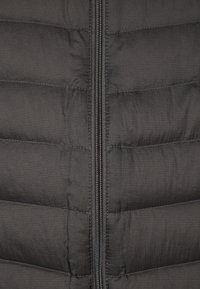 Sort pufferjakke med lodret syninger, der har en central lynlås, lavet af letvægts, tekstureret stof.