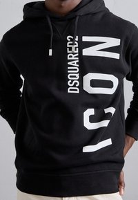 Sudadera con capucha negra con texto blanco "DSQUARED2" e "ICON". Presenta una capucha con cordón y puños acanalados. Hecha de tela suave y texturizada.