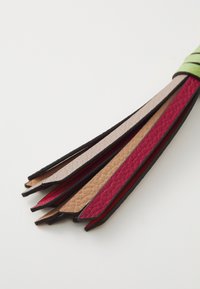 Sangles en cuir de différentes couleurs : rouge, beige et marron, présentant une surface texturée et une bordure lisse noire, disposées en forme d'éventail.