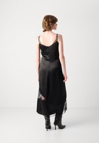 Schwarzes Satin-Kleid mit Spitzenbesatz am Saum, verstellbaren Trägern und taillierter Silhouette, mit einem tiefen Rückenausschnitt und Reißverschluss.
