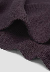 Tissu texturé violet profond avec une surface douce et légèrement pelucheuse, présentant des motifs tissés et un bord légèrement ondulé.