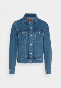 Džínová bunda, světle modrá, s klasickým designem zahrnujícím dvě náprsní kapsy, stříbrné kovové detaily, zapínání na knoflíky a mírně zkrácený lem.