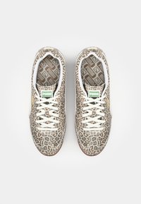 Tenisice s uzorkom leoparda, sa teksturiranom površinom, bijelim vezicama i zelenim Puma logom, koje imaju obložen uložak s uzorkom i smešnim gumastim đonom.