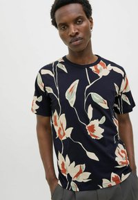 Tamsiai mėlyna marškinėliai su gėlių raštu kreminės, raudonos ir žalios spalvų. Trumpomis rankovėmis, apvaliu iškirpimu, pagaminti iš minkštos medžiagos, laisvas kirpimas.