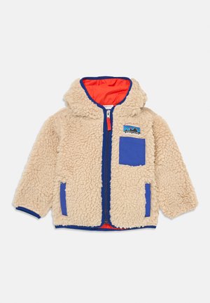 Veste en polaire beige avec capuche, accents bleus, zip frontal et poche poitrine. Intérieur doublé d'orange vif. Tissu texturé et doux.