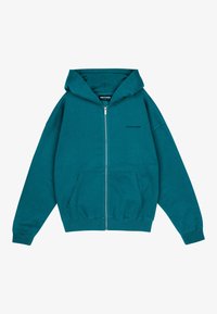 Felpa con zip di colore teal, dotata di tasca anteriore, cappuccio regolabile e polsini a coste. Presenta un branding sottile sul petto e un tessuto morbido e testurizzato.