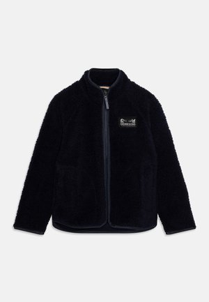 Fleece jacket in navy blue, featuring a high collar, front zipper, side pockets, and a textured surface. Logo patch on the left chest.