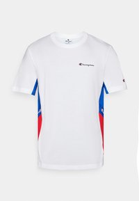 Camiseta blanca de algodón, con acentos en azul y rojo en las mangas, y un pequeño logo bordado en el pecho.
