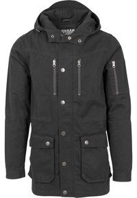 Giacca parka nera realizzata in tessuto resistente, con cappuccio, tasche sul petto con zip e chiusure a pressione. Due tasche inferiori frontali.