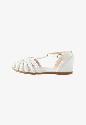 Weiße geflochtene Sandalen mit T-Riemen-Design, flacher Sohle und Knöchelschnalle. Glattes Material mit geschlossenem Fersenbereich und offenem Zehenstil.