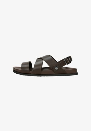 Bruine synthetische slide sandalen met kruislussen, een achtergesp voor aanpassing en een vlakke zwarte rubberen zool. Glad textuur en minimalistisch ontwerp.
