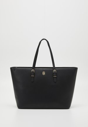 Zwarte leren shopper met dubbele schouderbanden en een klein logo-embleem in goudkleurig metaal aan de voorkant in het midden.