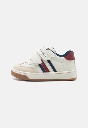 Hvid baby-sneaker med marineblå og røde striber, velcroremme og brun gummisål.