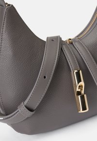 Harmaa nahkainen laukku, jossa on tekstuuri, kullanvärinen vetoketju ja kultainen lukko korostuksena sivussa. Varustettu säädettävällä hihnalla.