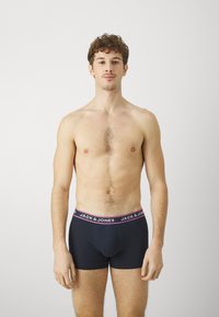 Schwarze Boxershorts mit einem elastischen Bund in Pink und Schwarz, beschriftet mit "JACK & JONES." Der Stoff wirkt glatt und enganliegend, entworfen für Komfort.