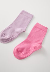 Bomullssockor i ljuslila och rosa, ribbad textur, med gummigrepp på sulorna för bättre grepp.