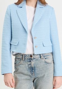Hellblau, strukturierte, kurze Jacke mit einem strukturierten Design, die einen Reverskragen, zwei Fronttaschen und silberne Knöpfe besitzt.