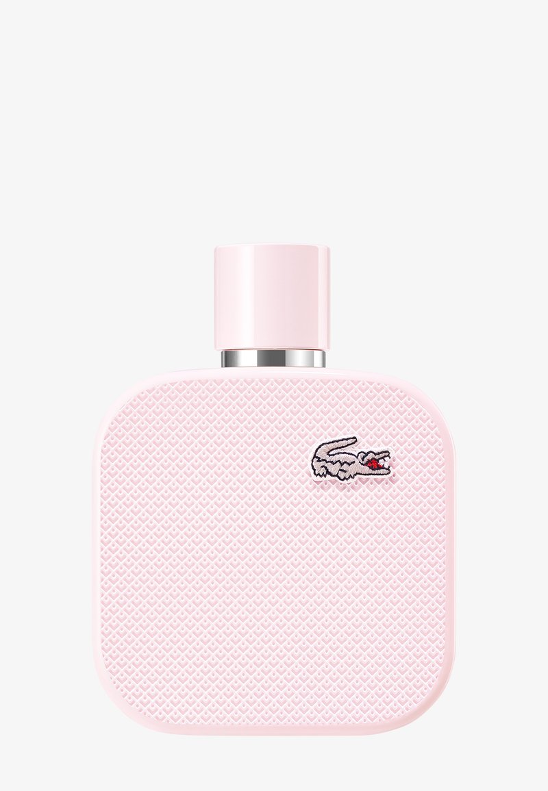 Vierkante roze parfumfles met een getextureerd oppervlak en een klein geborduurd krokodillenlogo rechtsboven.