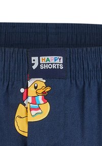 Marineblauwe shorts met een elastische tailleband, voorzien van een kleurrijk "Happy Shorts" label en een cartoon rubberen eend met een feestelijke sjaal en hoed.
