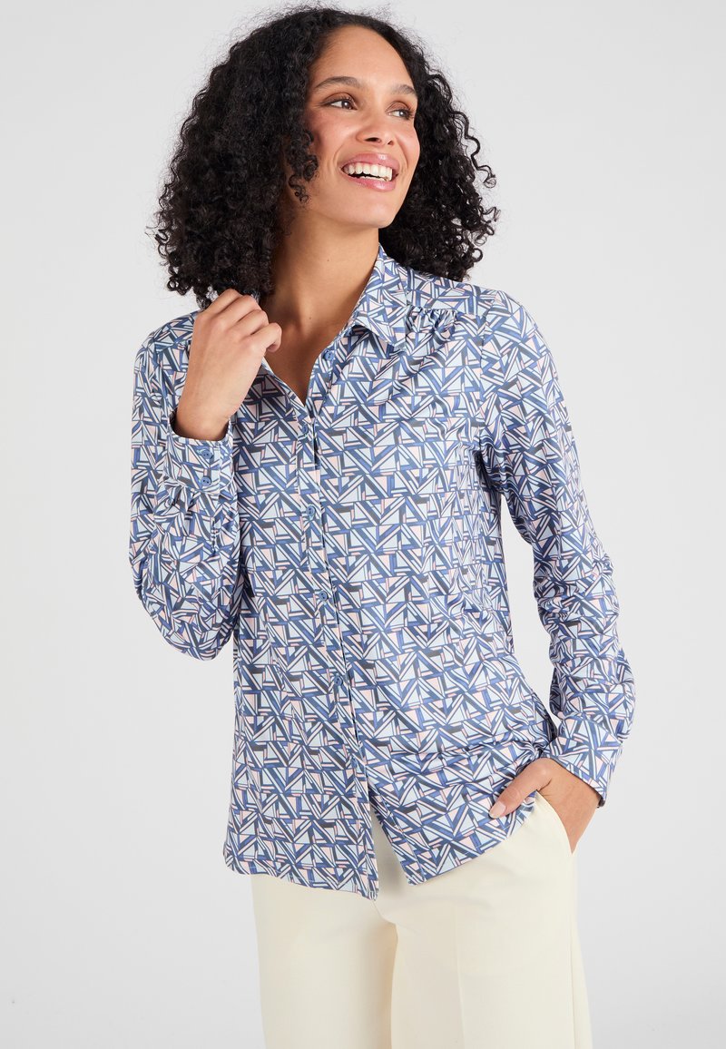 Camicia con maniche lunghe e bottoni blu con un motivo geometrico in bianco, rosa e navy. Tessuto morbido, vestibilità su misura e colletto appuntito.