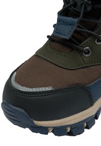 Hnědá a zelená turistická bota s texturovanou černou gumovou podrážkou, šedým šitím a zesílenou špičkou. Má kovové průvleky a tkaničky.