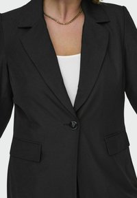 Črn blazer s strukturirano zasnovo, ki vključuje ovratnik z zarezo, enojno gumbno zapiranje in dva sprednja žepa. Gladka tekstura tkanine.