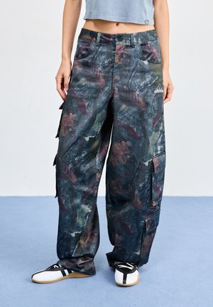 Pantalons cargo avec un motif de feuillage vert foncé et violet, dotés de plusieurs poches et d'un logo Adidas sur le côté droit.
