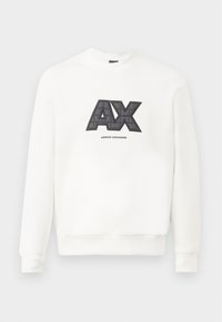 Fehér pulóver puha anyagból. Jellegzetes fekete és szürke „AX” logóval rendelkezik, amely steppelt textúrájú, és alatta az „ARMANI EXCHANGE” felirat található.