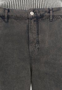 Tamno sivi pamukasti hlače s glatkom teksturom, sa metalnim dugmetom i ušivenim džepovima na struku, minimalnog dizajna.