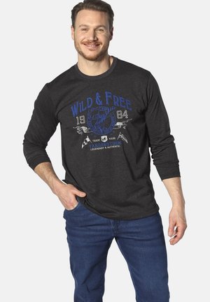 Black long-sleeve shirt with blue graphic text "WILD & FREE" and emblem. Paired with blue jeans, the t-shirt features a round neckline and regular fit.
