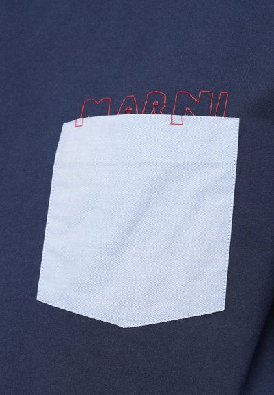 Námornícke tričko s svetlomodrou štvorcovou kapsou a červeným prešívaním, na ktorom je zobrazené slovo "MARNI" v tučnom, kontúrovom písme.