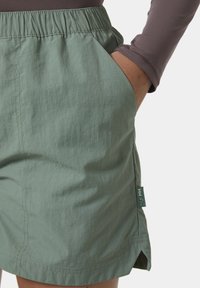 Pantalones cortos verde claro hechos de una tela texturizada con una cintura elástica, bolsillos laterales y una pequeña etiqueta de la marca en un lado.