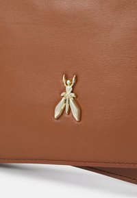 Borsa a mano in pelle marrone con un'emblema d'insetto dorato e ali trasparenti, che mette in risalto il materiale testurizzato e i dettagli accurati.