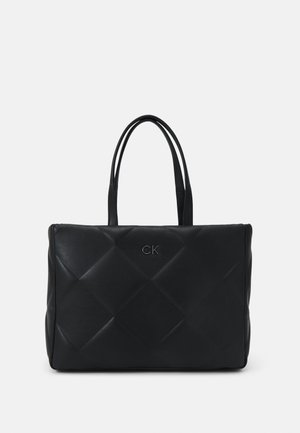 Borsa tote in pelle nera con design trapuntato. Presenta il logo "CK" in rilievo e doppi manici. Texture liscia con una forma strutturata.