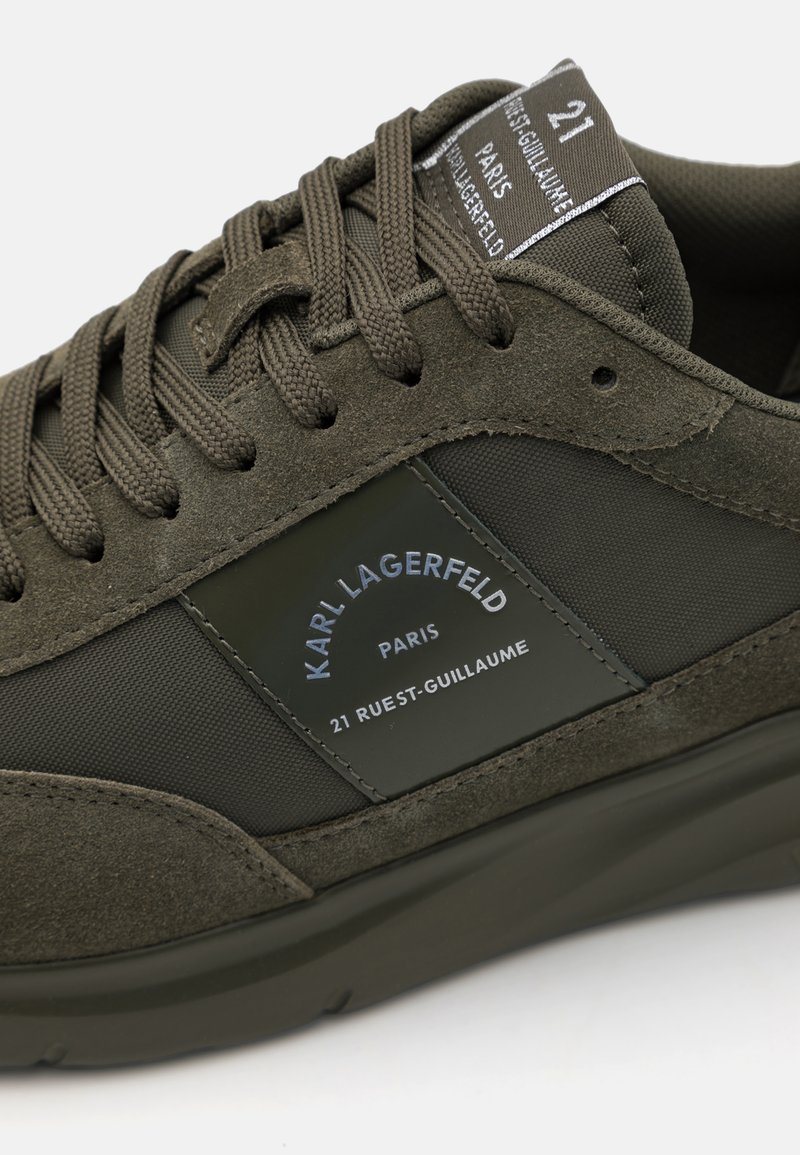 Oliwkowe sneakersy wykonane z połączenia zamszu i gumy, z teksturowaną powierzchnią, grubymi sznurowadłami i naszywką z logo po boku.