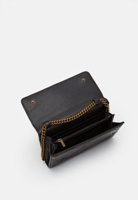 Black leather clutch bag open to show interior compartments and gold chain strap on a white background.